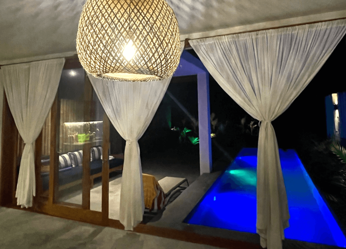 Piscina con vista infinita, al anochecer, frente a la sala de una de las casas del minicondominio Hale Beach, proyecto de Green Dreams en Punta Sal
