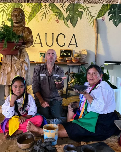 Mujer y niña de la selva compartiendo saberes ancestrales en cerámica junto a visitante en Mundo Yanashpa, Tarapoto. Actividad cultural en el espacio Auca, con piezas hechas a mano y elementos de la selva.