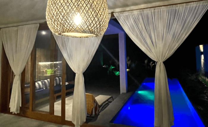 Piscina con vista infinita, al anochecer, frente a la sala de una de las casas del minicondominio Hale Beach, proyecto de Green Dreams en Punta Sal