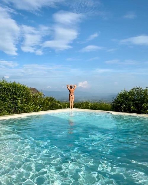 Mujer disfrutando de la piscina infinita con vista a la selva amazónica desde Green Dreams Resort en Tarapoto, rodeada de naturaleza y cielo despejado.
